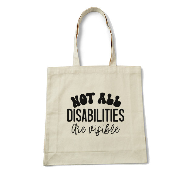 Beige tote bag with black text 'Not all disabilities are visible' on a white background